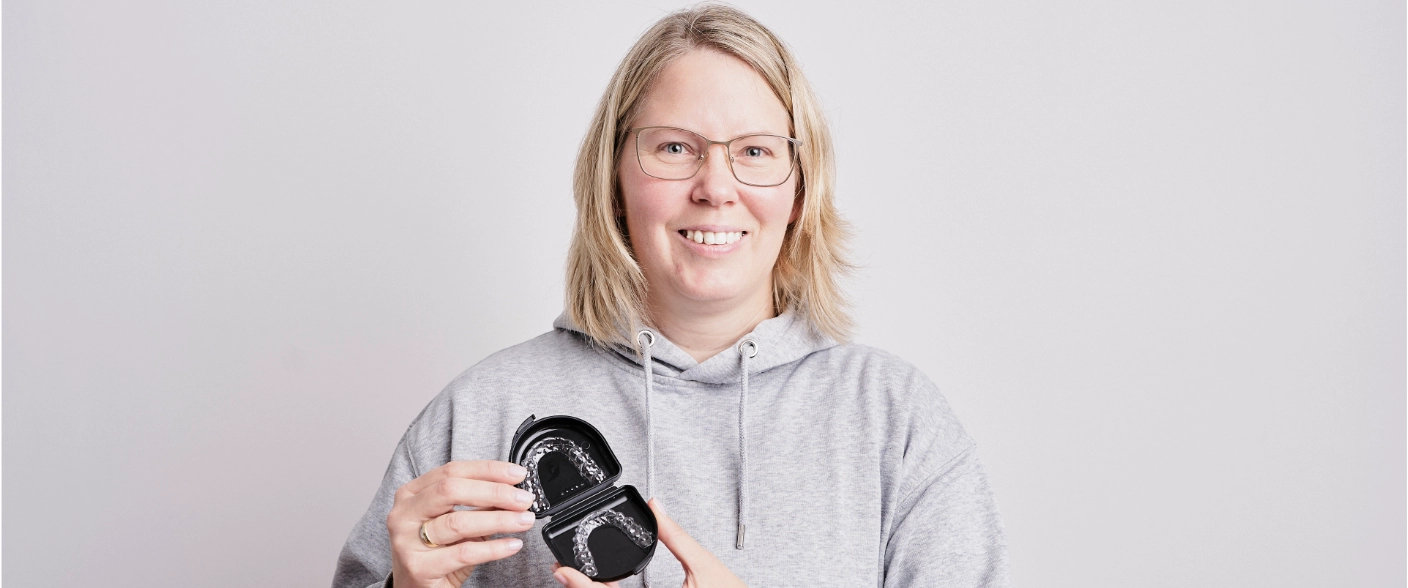 Lady is happy about aligner therapy and shows her aligners.