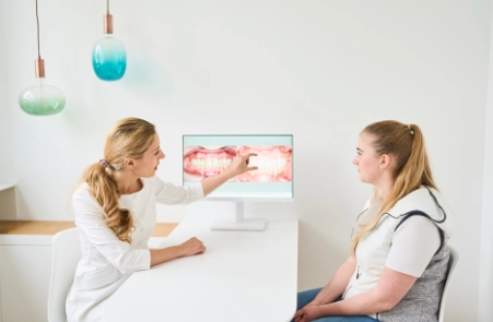 Das ganzheitliche KFO360° Konzept erklärt Kieferorthopädin Dr. Theresa Jilek in KFO Praxis München Süd einer Patientin und gibt eine individuelle Beratung zu Zahnspangen.