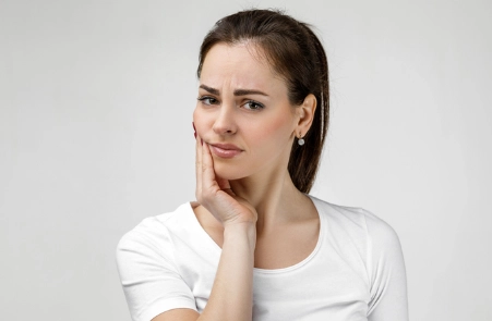 Frau mit schmerzverzehrtem Gesicht wegen Kiefergelenkknacken, Kieferschmerzen wegen CMD